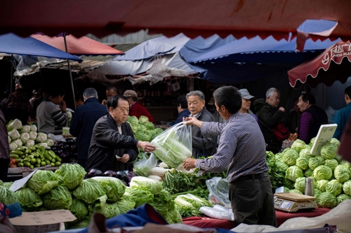 Người dân mua đồ tại một khu chợ ở Bắc Kinh (Trung Quốc). Ảnh: AFP